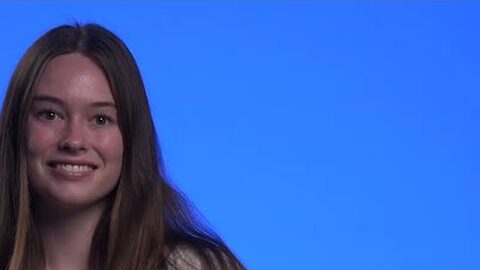 Bridget, smiling, in front of a blue background.